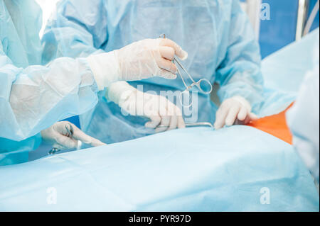 Le chirurgien et son assistant travaillant sur un patient au cours d'une intervention chirurgicale à l'hôpital salle d'opération. Instrument de chirurgie chirurgien holding au cours de procédure médicale Banque D'Images