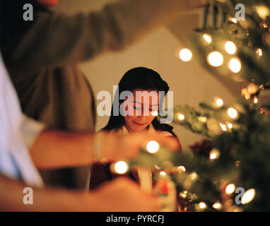 Girl decorating Christmas Tree avec la famille Banque D'Images