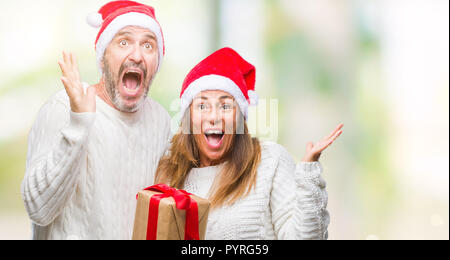 L'âge moyen hispanic couple wearing christmas hat don sur fond isolé très heureux et excité, lauréat expression célèbre victo Banque D'Images