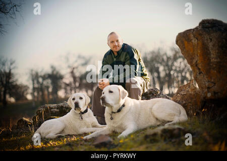 Portrait d'un homme assis sur un rocher avec ses chiens. Banque D'Images