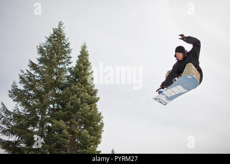 Jeune homme équitation son snowboard à la mi-air. Banque D'Images