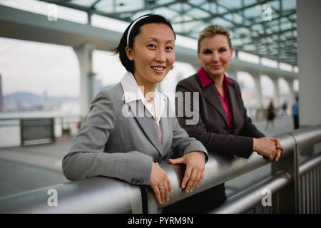 Portrait of a smiling businesswoman standing lors d'une balustrade avec son collègue. Banque D'Images