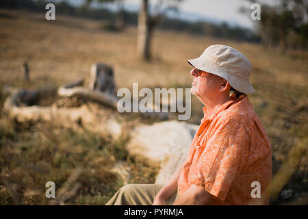 Senior homme assis dans un champ. Banque D'Images