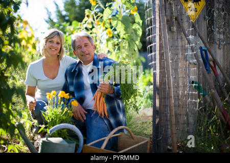 Portrait of a smiling young couple assis dans leur jardin. Banque D'Images