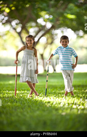 Frère et sœur posant pour une photo en s'appuyant sur le croquet maillets. Banque D'Images