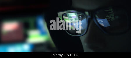 Hacker Nerd à lunettes qui travaillent avec un ordinateur dans le noir, la cybersécurité concept Banque D'Images