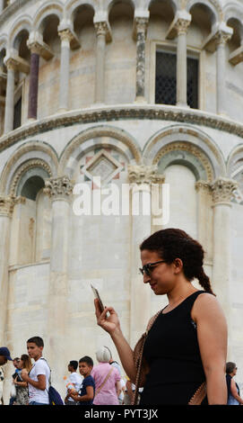 Une femme à l'aide de son téléphone portable par la tour penchée de Pise. Banque D'Images