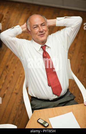Senior businessman sitting at desk, à l'espoir. Banque D'Images