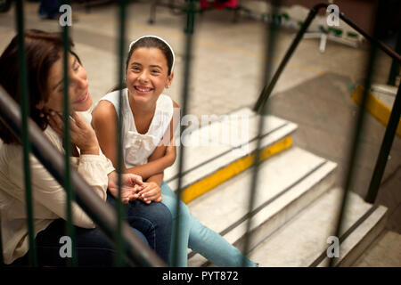 Femme et sa petite-fille assise sur les marches à une station de train. Banque D'Images