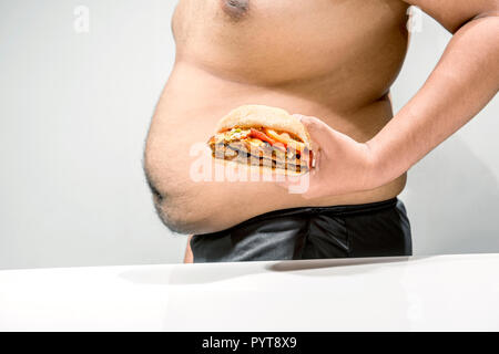 L'homme à l'excès de ventre holding hamburger sur sa main sur fond blanc Banque D'Images