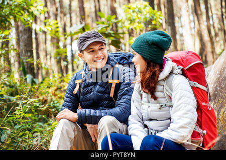 Smiling asian couple randonneurs avec sac à dos à l'un l'autre sur la forêt Banque D'Images