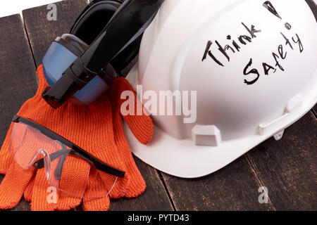 De Protection individuelle sécurité euipment (casque, gants, lunettes, protection de l'oreille) sur une table en bois noir sur blanc fond isolé. La sécurité d'abord conce Banque D'Images