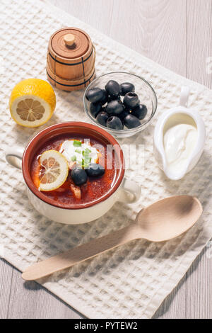 Saltwort soupe à la viande, saucisses fumées, pommes de terre, tomates, concombre mariné mariné, citron, olives noires et la crème sure dans un bol à soupe en céramique avec Banque D'Images