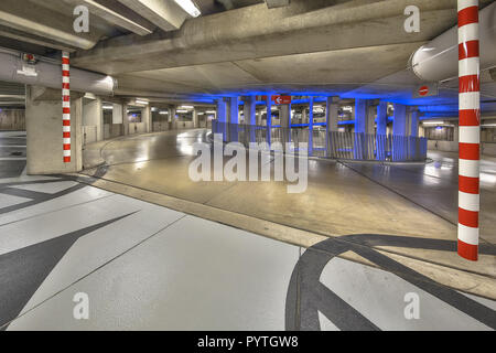 Rampe vide circulaire dans parking souterrain avec éclairage coloré sous un centre commercial du centre-ville Banque D'Images