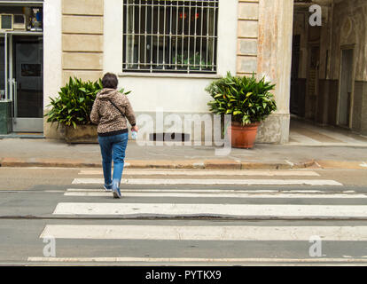 Touriste à Milan traverse la route rapidement à un passage pour piétons, la vue de l'arrière Banque D'Images