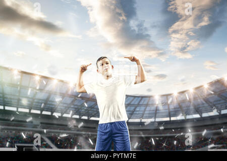 Jeune garçon comme gagnant à stade. jeunes football joueur de football en mouvement sur fond de ciel. Collage Banque D'Images