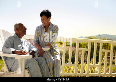 Couple assis sur leur terrasse en pyjama. Banque D'Images