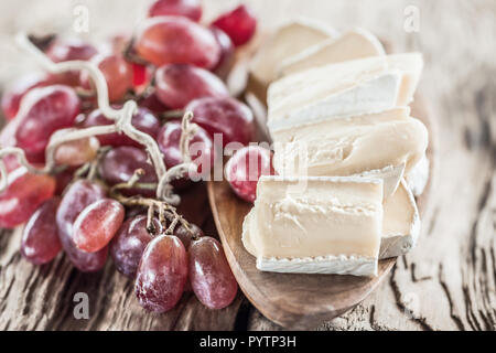 Maison bio fromage brie blanc avec raisins rose sur une planche en bois Banque D'Images