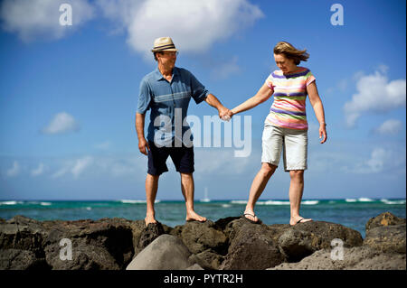 Couple marche main dans la main le long d'une côte rocheuse. Banque D'Images