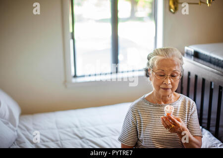 Femme âgée lit les instructions sur son flacon de médicaments. Banque D'Images