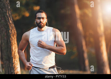 Multicultural beau barbu dans les vêtements de sport à l'écoute sa musique préférée et avoir son matin tournant à la forêt, les modes de vie et de personnes concept Banque D'Images