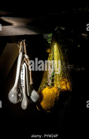 Cuillères de mesure céramique accroché à côté de sac de citrons dans la cuisine Banque D'Images