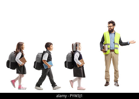 De toute la longueur de marche des écoliers dans une ligne et un enseignant avec un gilet de sécurité et les gestes avec la main isolé sur fond blanc Banque D'Images