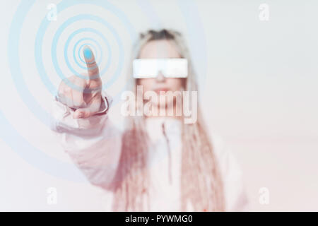 Jeune femme en vêtements futuristes de toucher l'écran virtuel Banque D'Images