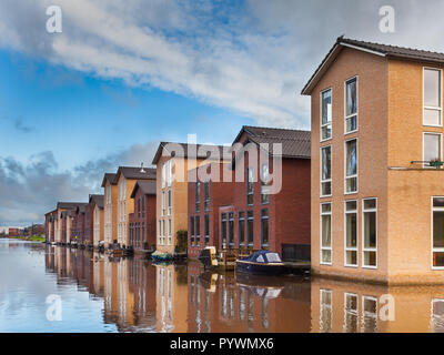 Maisons modernes sur le front de mer dans une rangée avec jetty et bateaux Banque D'Images