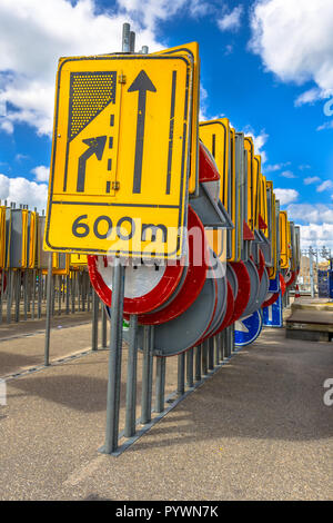 Le rétrécissement de la route jaune signe parmi d'autres lignes de signalisation routière attendent d'être embauchés dans des projets de construction de routes Banque D'Images