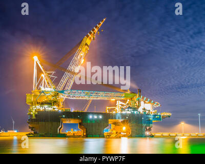 Pose de énorme navire Crane amarré dans un port et éclairée par des lumières au coucher du soleil Banque D'Images