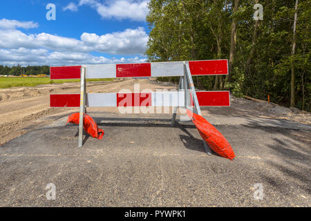 Le rouge et blanc aucune barrière d'entrée sur une petite route de campagne asphaltée Banque D'Images