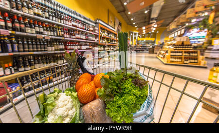 Panier d'épicerie dans un supermarché rempli avec de l'allée des produits alimentaires sains vu depuis le point de vue des clients Banque D'Images