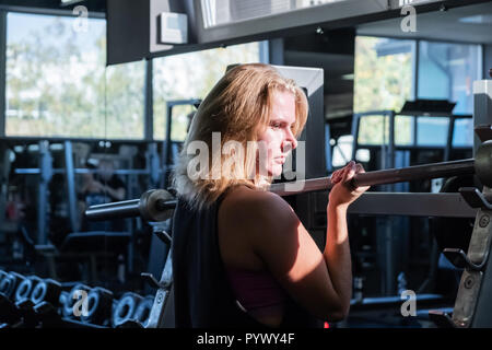 Jeune femme monter à la salle de gym faire heavylifting l'exercice. Athlète féminin à une salle de remise en forme l'élaboration avec barbell Banque D'Images