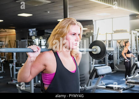 Jeune femme monter à la salle de gym faire heavylifting l'exercice. Athlète féminin à une salle de remise en forme l'élaboration avec barbell Banque D'Images