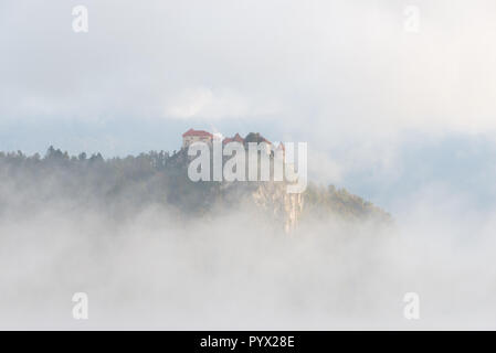 Le Château de Bled sur une falaise surplombant le lac de Bled entouré par des nuages et brouillard au sol créant l'illusion qu'il est construit dans le ciel en Slovénie. Banque D'Images