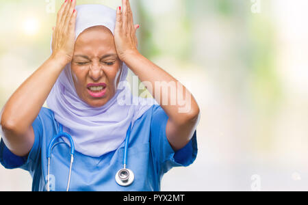 L'âge moyen des infirmières arabes senior woman wearing hijab sur fond isolés souffrant de maux désespérés et souligné parce que la douleur et la migraine. Ha Banque D'Images