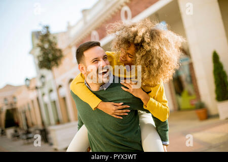 Jeune homme est titulaire d'une jeune femme sur son dos et divertissante themselvs outdoor Banque D'Images