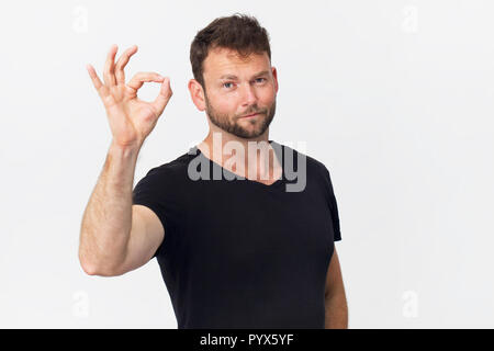 Des hommes souriant avec aspect attrayant, porter t-shirt noir, posant contre un mur blanc vide Banque D'Images