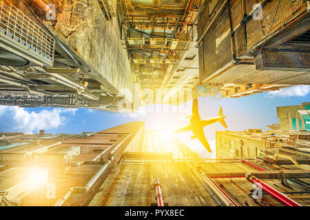 Vue du dessous des gratte-ciel de vol d'un avion sur le quartier de Kowloon à Hong Kong, Chine. La construction urbaine encombrée avec lumière du soleil du ciel au coucher du soleil. Banque D'Images