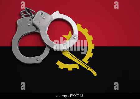 Drapeau de l'Angola et la police menottes. La notion de crime et de délits dans le pays. Banque D'Images