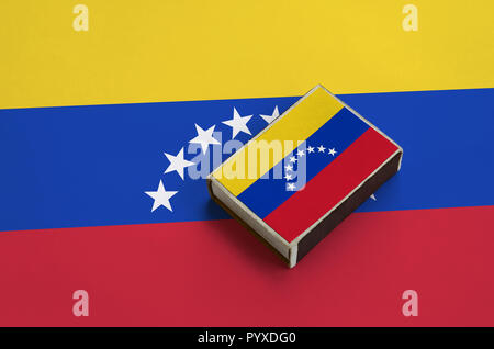 Le Venezuela drapeau est représenté sur une boîte d'allumettes qui se trouve sur un grand drapeau. Banque D'Images