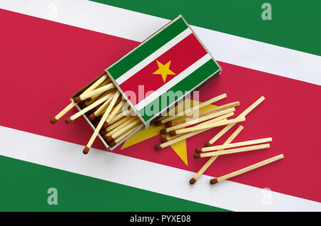 Suriname drapeau est indiqué sur une boîte d'allumettes, à partir de laquelle plusieurs matches de l'automne et se trouve sur un grand drapeau. Banque D'Images