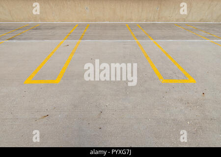 Places de stationnement vide avec lignes jaunes dans un parking couvert. Banque D'Images