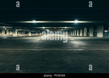 Grungy, faiblement éclairées garage parking vide avec éclairage vertical et un panneau de sortie qui pendent du plafond. Banque D'Images