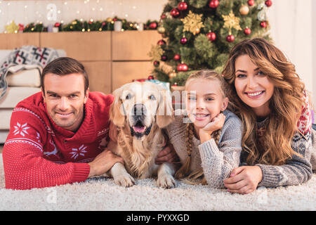 Famille avec chien golden retriever couché près de l'ensemble de l'arbre de Noël Banque D'Images