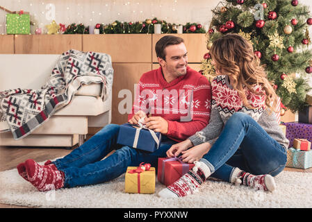 Mari et femme de l'ouverture des cadeaux de Noël et à la recherche à l'autre à la maison Banque D'Images