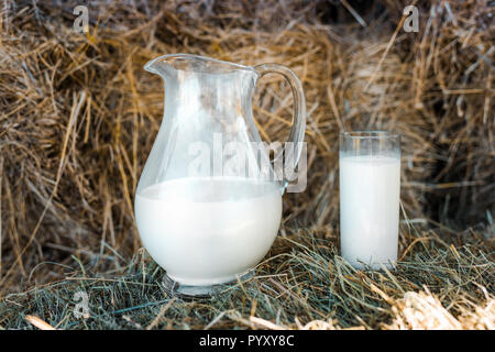 Focus sélectif de la verseuse et le verre de lait sur meules de foin à la ferme Banque D'Images