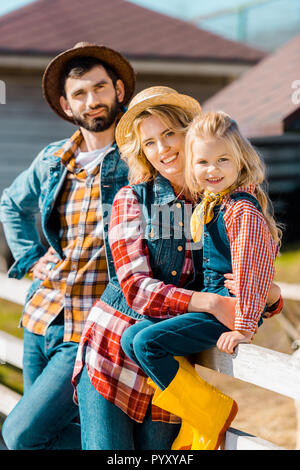 Focus sélectif de happy farmer famille avec petite fille assise sur une clôture en bois au ranch Banque D'Images