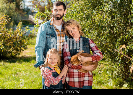 Happy Farmer famille avec petite fille et lapin brun à l'extérieur Banque D'Images